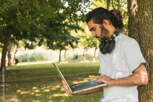 Man standing under a tree with a laptop
