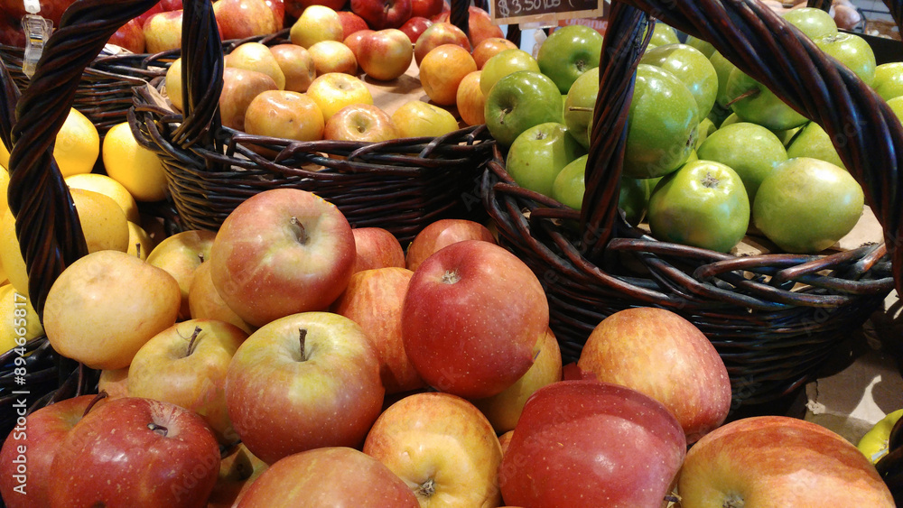 Shiny, fresh green Granny Smith and Macintosh apples in wicker baskets at a farmer's market.