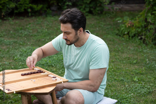 Young man playing backgammon outdoors photo