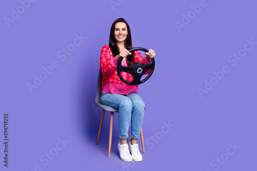 Full length photo of charming positive woman wear pink cardigan riding car empty space isolated purple color background © deagreez