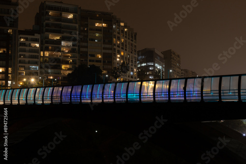 A bridge with a blue lighted railing is shown at night. Miraflores, Peru photo