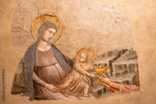 Close-up on religious fresco painted on wall portraiting Virgin Mary with Jesus as a boy receiving a golden cup