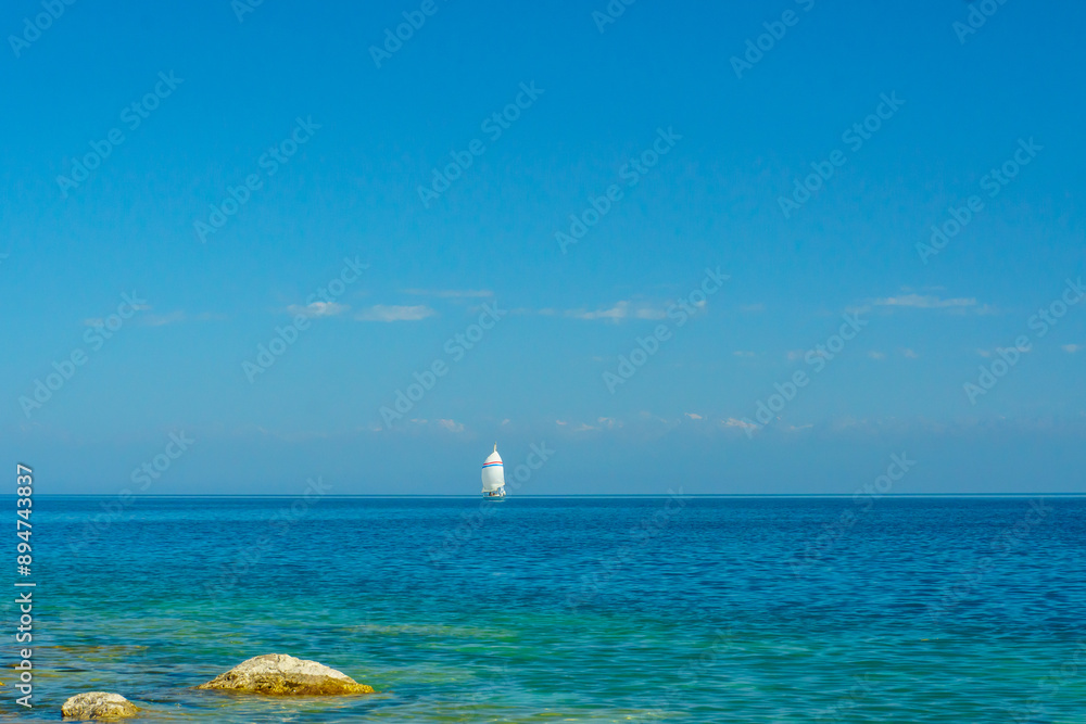 Single sailboat navigating Issyk-Kul Lakes waters. Skilled sailors navigate Sailing, recreational maritime sport. Yacht, Wind harnessing, sail trimming. Aquatic velocity pursuit, boating experience. Single sailboat navigating Issyk-Kul Lakes waters. Skilled sailors navigate Sailing, recreational maritime sport. Yacht, Wind harnessing, sail trimming. Aquatic velocity pursuit, boating experience.