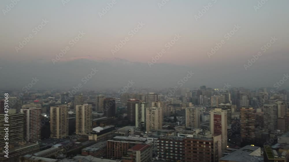 Aerial drone view of Santiago, Chile, shrouded in winter haze with the Andes mountains visible in the background, highlighting the city's foggy atmosphere and dramatic landscape. Aerial drone view of Santiago, Chile, shrouded in winter haze with the Andes mountains visible in the background, highlighting the city's foggy atmosphere and dramatic landscape.