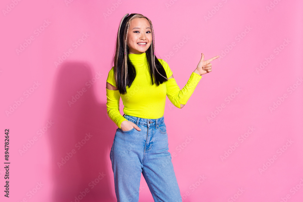 Photo of positive girl with dyed hair dressed yellow turtleneck directing at discount empty space isolated on pink color background Photo of positive girl with dyed hair dressed yellow turtleneck directing at discount empty space isolated on pink color background