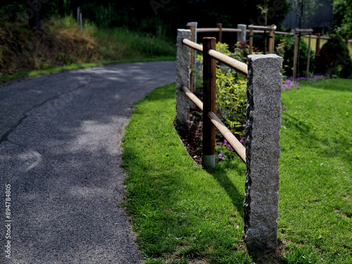 rural fencing made of hewn stove posts style enclosure in the mountains. a bed mulched with bark and perennial blue flowers along the edge photo