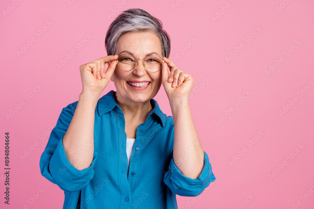 Photo portrait of lovely pensioner lady touch specs dressed stylish blue garment isolated on pink color background Photo portrait of lovely pensioner lady touch specs dressed stylish blue garment isolated on pink color background