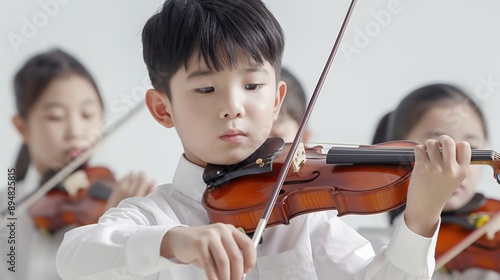 Young Asian boy playing the violin in a music class