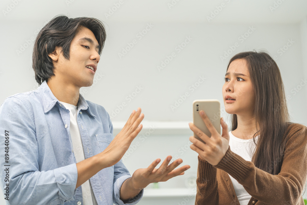 Infidelity, suspicion asian young couple love fight relationship, wife holding cellphone, smartphone cheating on phone, scolding husband about mistrust, distrust and jealousy at home. Infidelity, suspicion asian young couple love fight relationship, wife holding cellphone, smartphone cheating on phone, scolding husband about mistrust, distrust and jealousy at home.