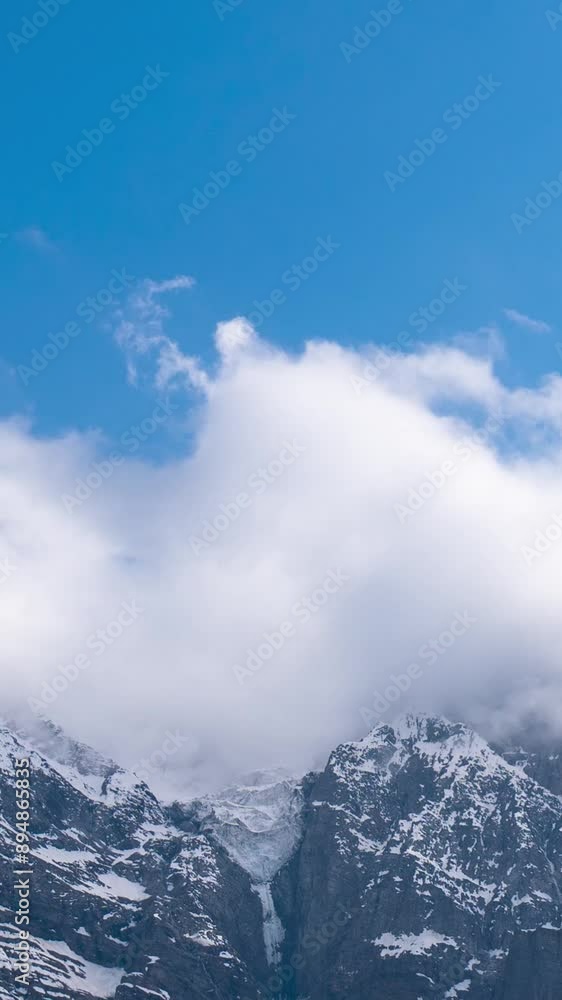 Vertical Time-lapse shot of clouds rolling above the snowy Himalayas as seen from Khangsar Village in Lahaul, Himachal Pradesh, India. Clouds cover the mountain peaks and roll around them. Vertical Time-lapse shot of clouds rolling above the snowy Himalayas as seen from Khangsar Village in Lahaul, Himachal Pradesh, India. Clouds cover the mountain peaks and roll around them.