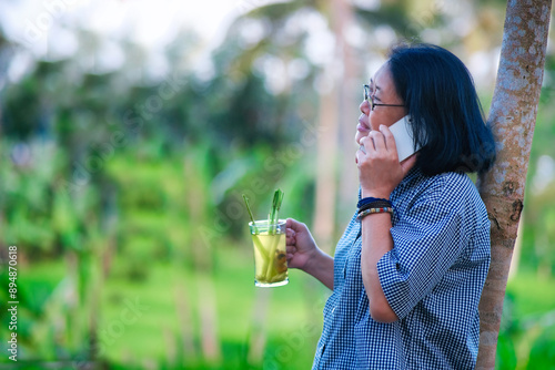 A woman talking on the phone is holding a glass of hot drink photo