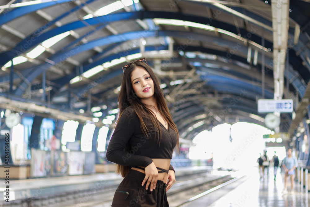Fototapeta premium Young woman standing on a metro station platform and waiting for a metro train. People travel in public transport concept.