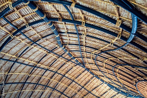 Beautiful thatched roof surface detail of mixed materials pattern structure by weave pile straw with steel bars. .Roof​ made​ of​ straw. Pattern of under bamboo roof frame..Wooden thatched ceiling.