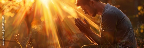 Man Praying in Golden Sunlight - A man kneeling in a field, hands clasped in prayer, with sunlight shining down on him. This symbolizes faith, hope, gratitude