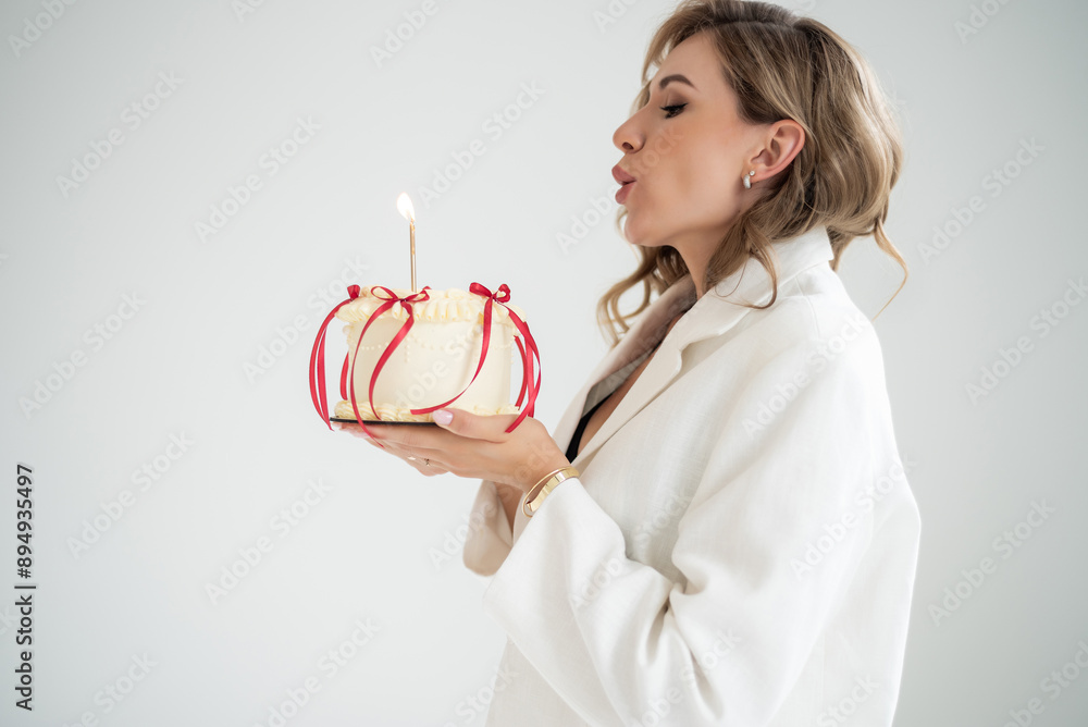 Happy woman wearing formal white suit holding birthday cake and celebrating Happy woman wearing formal white suit holding birthday cake and celebrating