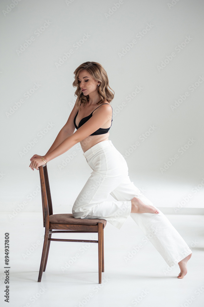 young beautiful woman in formal clothes posing on a chair in studio young beautiful woman in formal clothes posing on a chair in studio