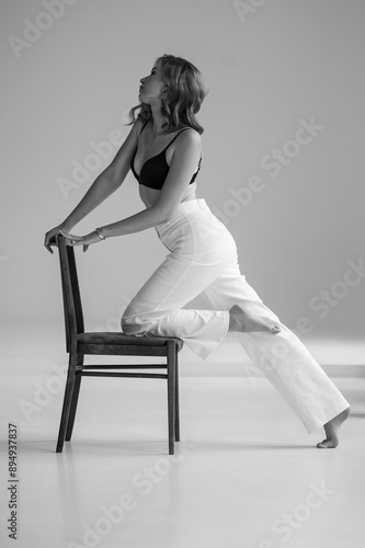 young beautiful woman in formal clothes posing on a chair in studio