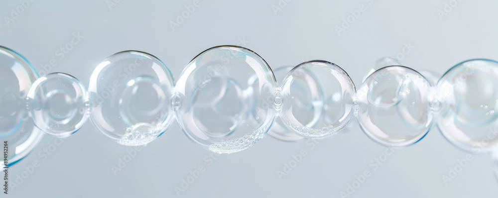 Large, perfectly round bubbles floating in a line against a white background, showing their translucent nature. Large, perfectly round bubbles floating in a line against a white background, showing their translucent nature.