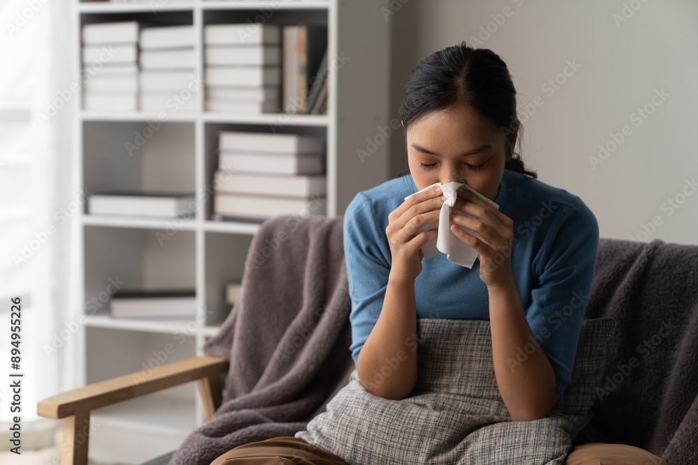 A photograph depicting a female individual in a state of discomfort seated upon a sofa within a residential setting. A photograph depicting a female individual in a state of discomfort seated upon a sofa within a residential setting.