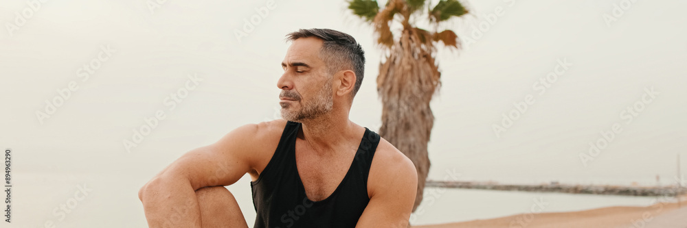 Middle-aged muscular man sitting on the promenade after jogging, panorama Middle-aged muscular man sitting on the promenade after jogging, panorama