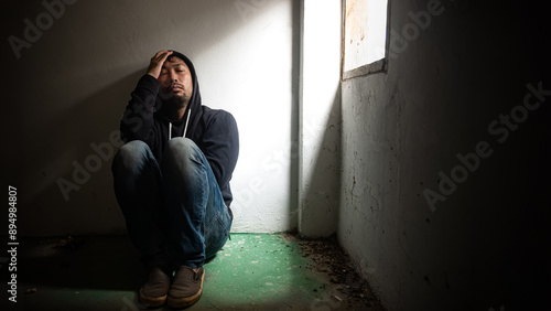 Fotografie adult man junkie Sitting blankly in a dark room near the window