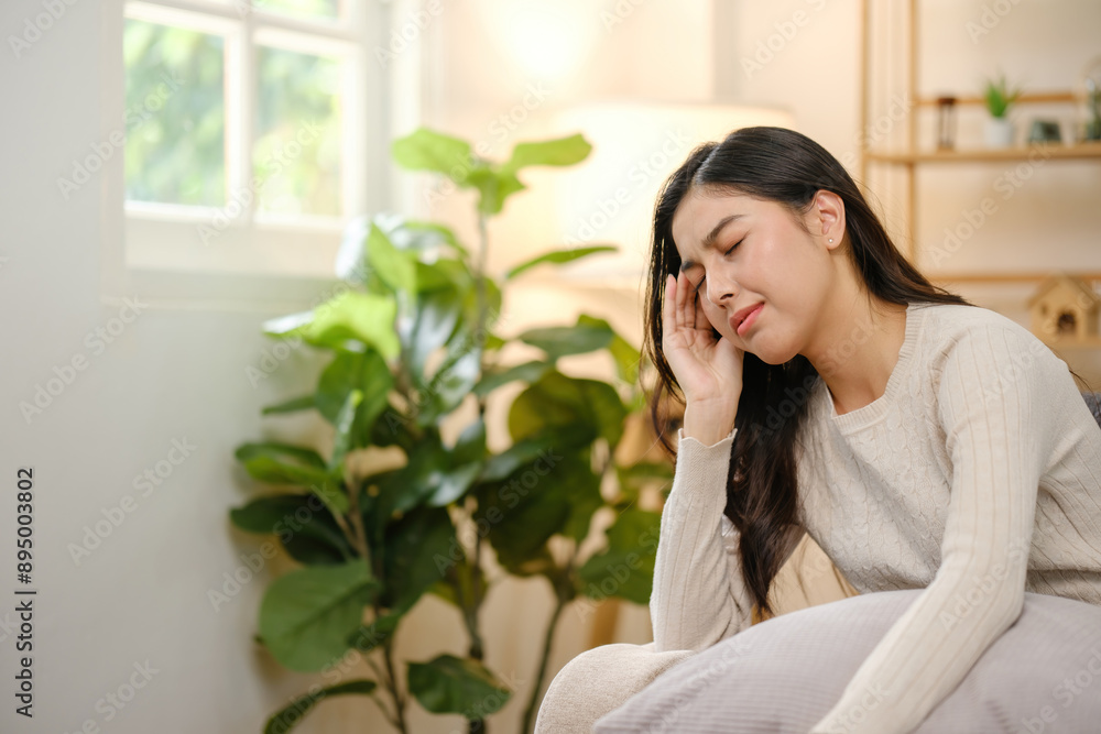 A woman is sitting on a couch with her head in her hands