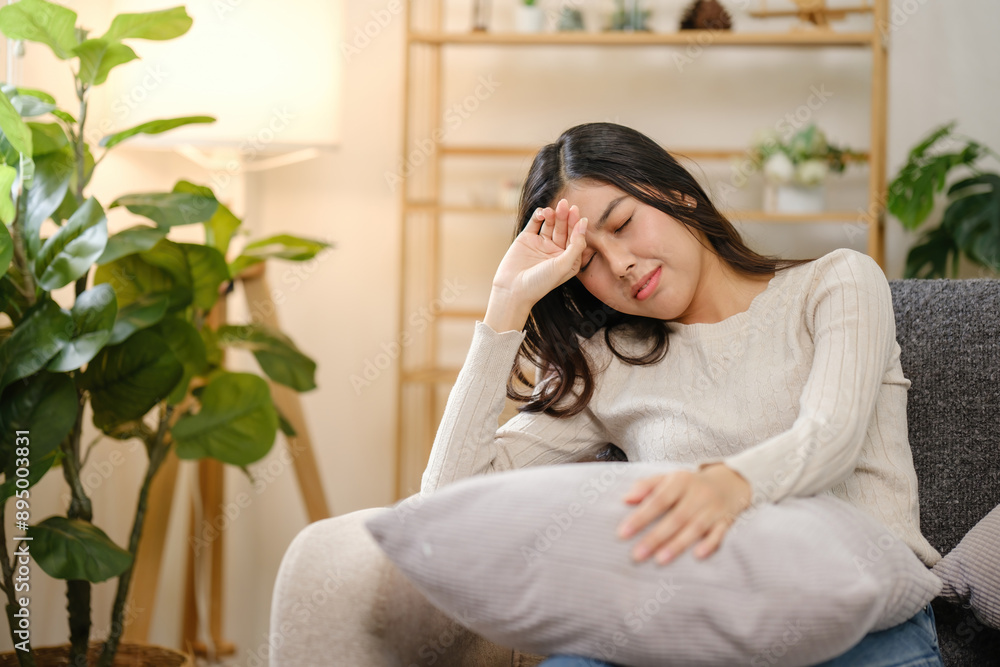 A woman is sitting on a couch with a pillow on her lap A woman is sitting on a couch with a pillow on her lap