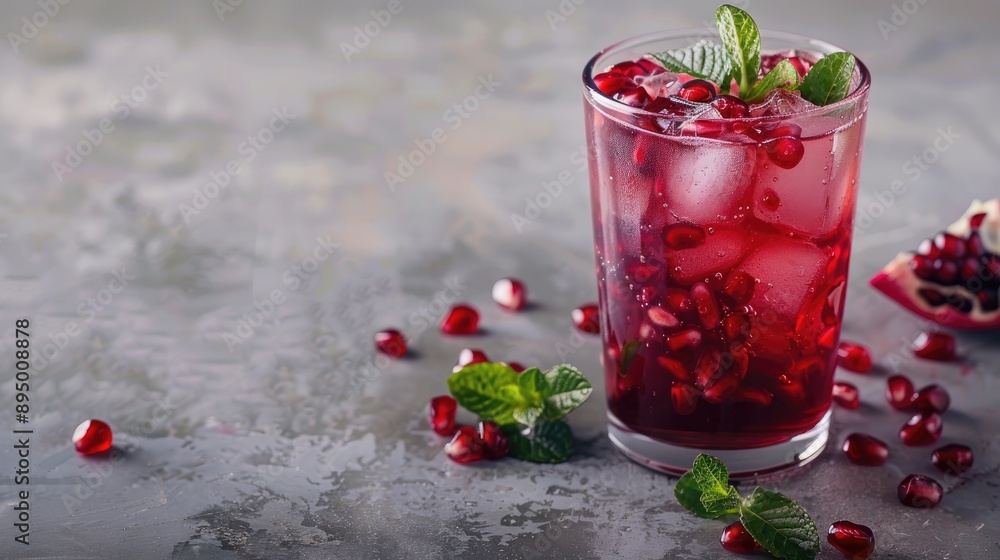 Refreshing pomegranate juice with ice and mint served in a clear glass on a grey background Benefits of nutritious diet Refreshing pomegranate juice with ice and mint served in a clear glass on a grey background Benefits of nutritious diet