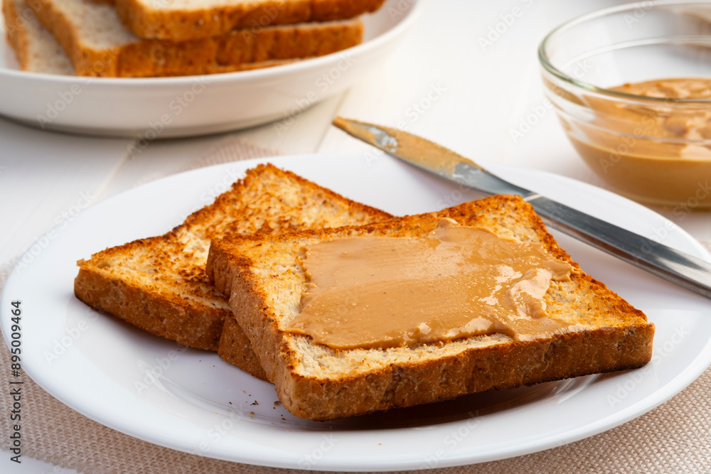 Toast bread and Homemade peanut butter.Spreading peanut butter on slice whole wheat bread in white plate. Toast bread and Homemade peanut butter.Spreading peanut butter on slice whole wheat bread in white plate.
