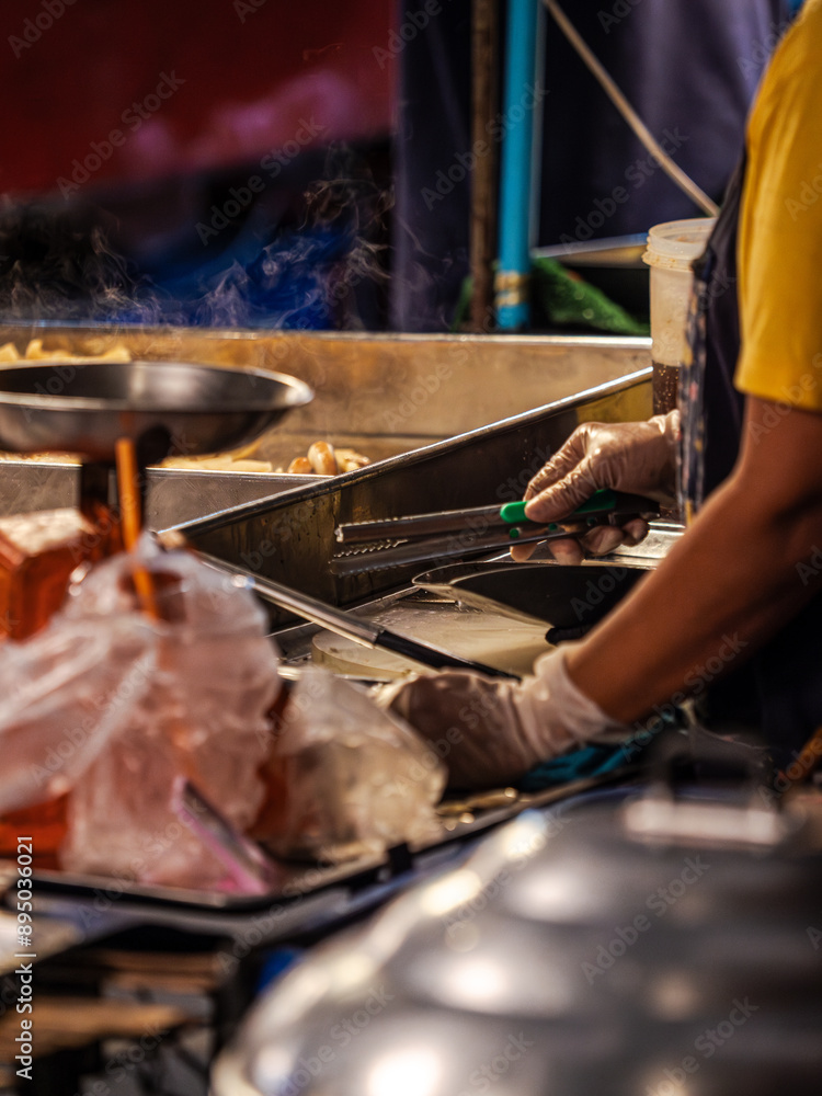 A street food vendor prepares food at a night market A street food vendor prepares food at a night market