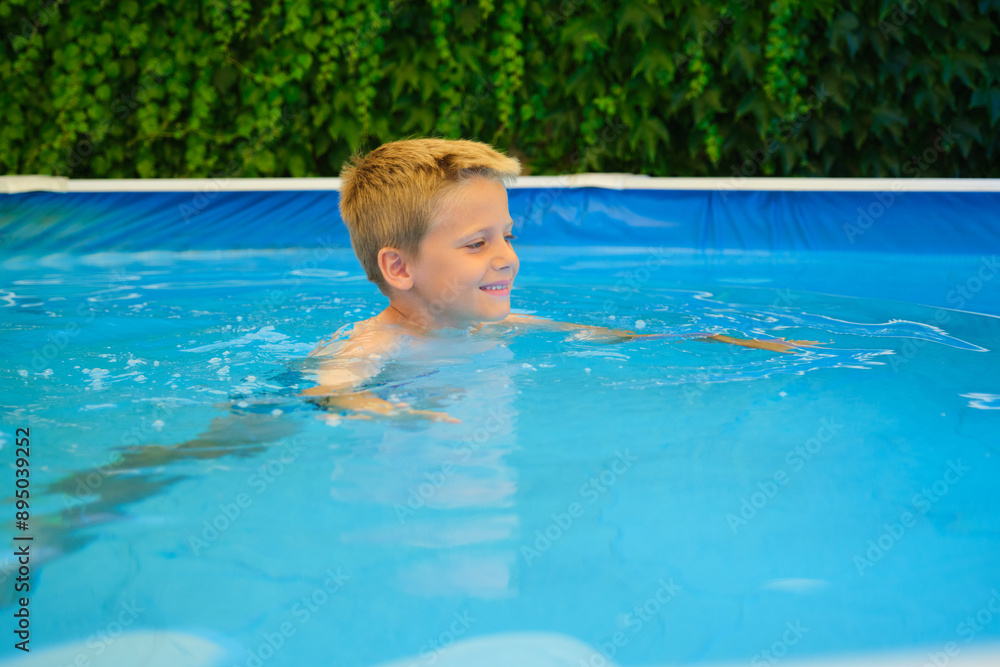 Young boy is happily swimming in a backyard pool during a summer day Young boy is happily swimming in a backyard pool during a summer day