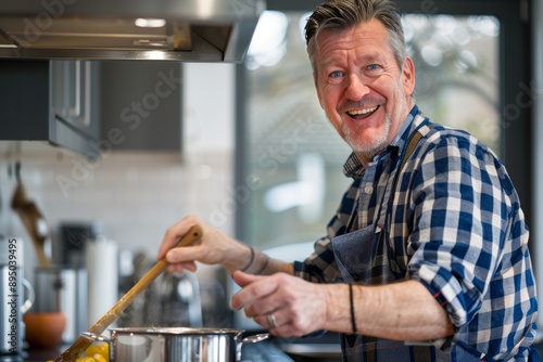 An engaging close-up of a middle aged man happily cooking in a modern kitchen