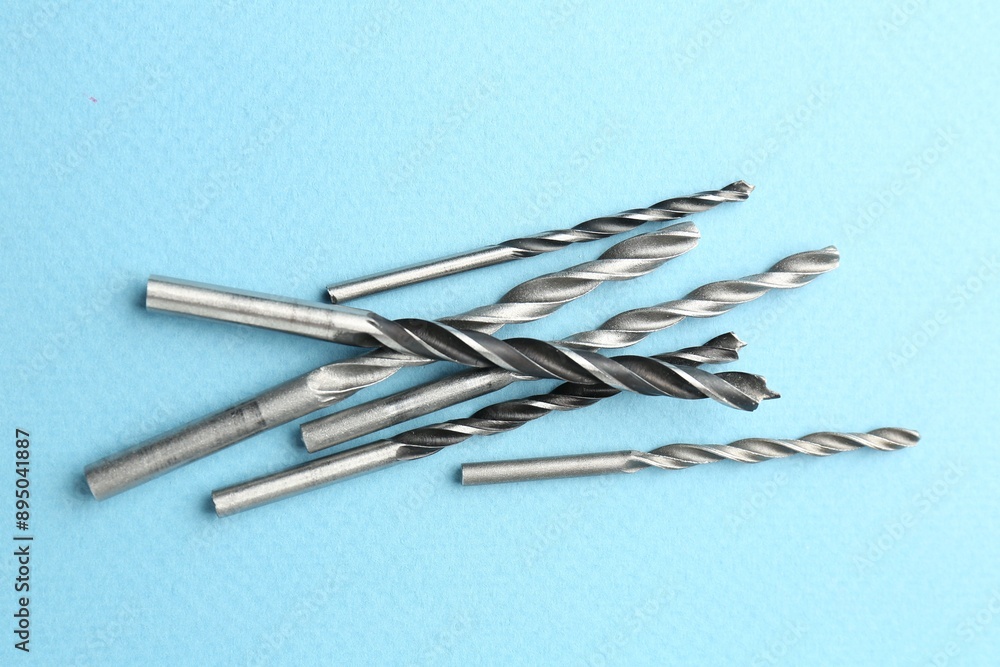 Many different drill bits on light blue background, top view Many different drill bits on light blue background, top view