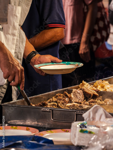 Photography A vendor serves meat from a large metal tray to a customer