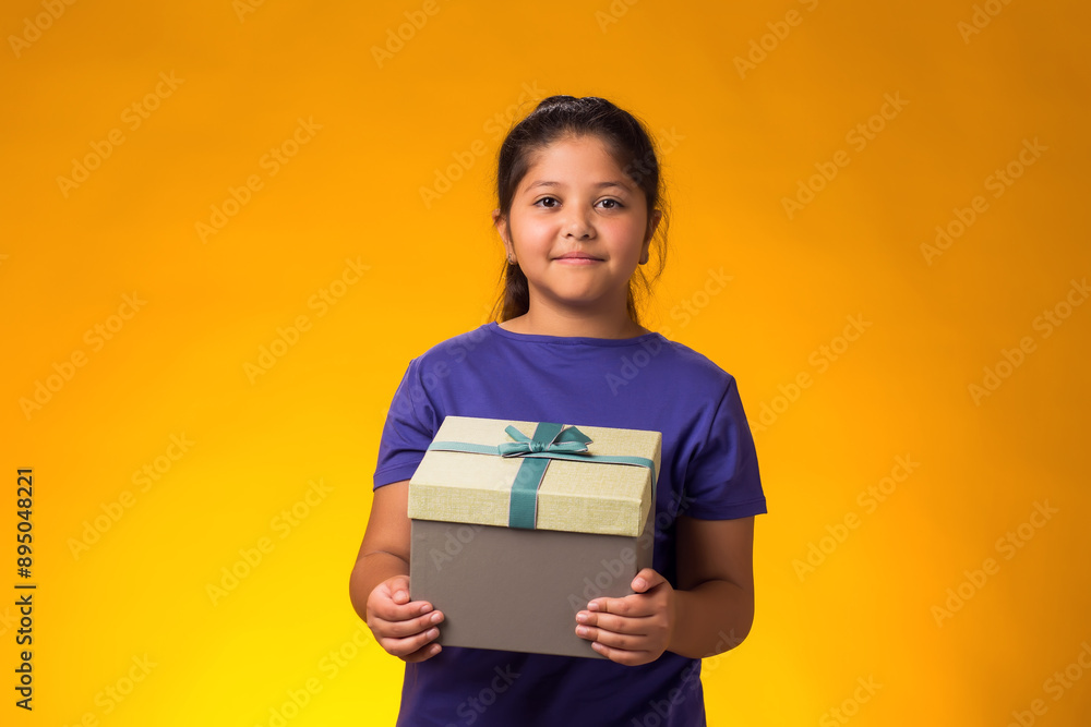 Smiling kid girl holding giftbox over yellow background. Birthday and celebration concept Smiling kid girl holding giftbox over yellow background. Birthday and celebration concept
