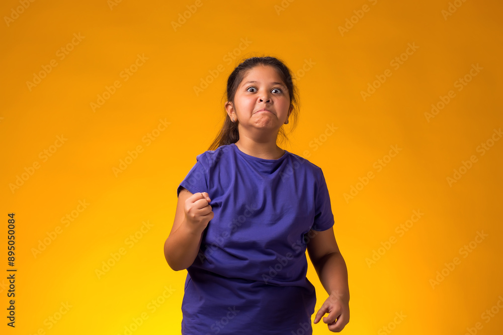 Enraged Child girl showing fist at camera on yellow background. Negative emotions concept Enraged Child girl showing fist at camera on yellow background. Negative emotions concept