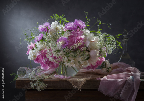 Still life with a bouquet of peonies, cornflowers and jasmine on a dark background