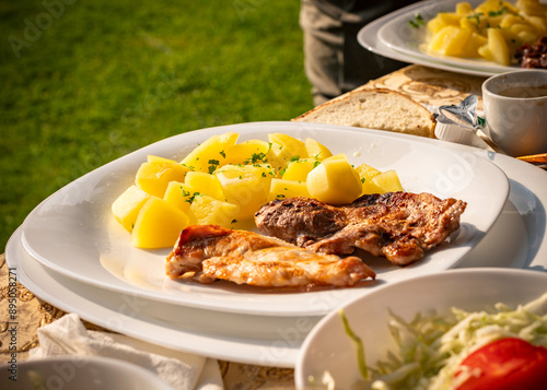 simple and tasty menu, natural potatoes soaked in butter and flavored with parsley and barbecued pork, at a garden party in a summer afternoon photo