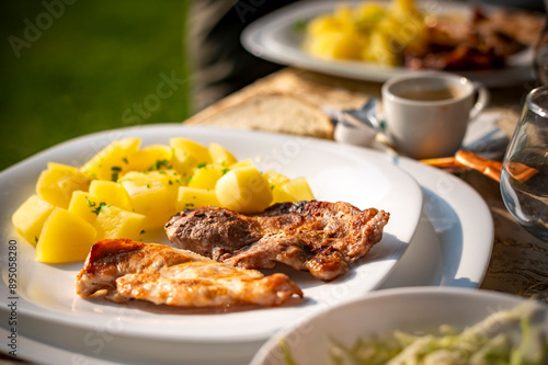 simple and tasty menu, natural potatoes soaked in butter and flavored with parsley and barbecued pork, at a garden party in a summer afternoon photo