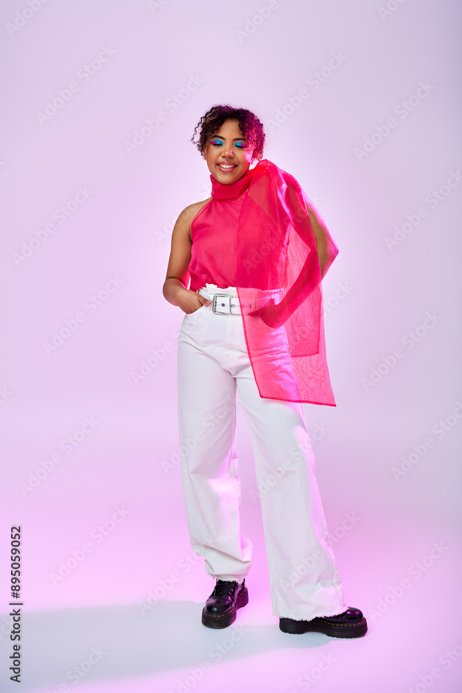 African American woman poses gracefully in white pants and pink top on vibrant backdrop. African American woman poses gracefully in white pants and pink top on vibrant backdrop.