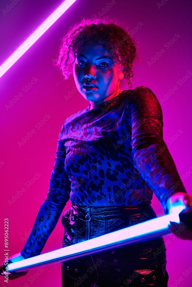 A striking African American woman wields a LED lamp in a dimly lit room. A striking African American woman wields a LED lamp in a dimly lit room.