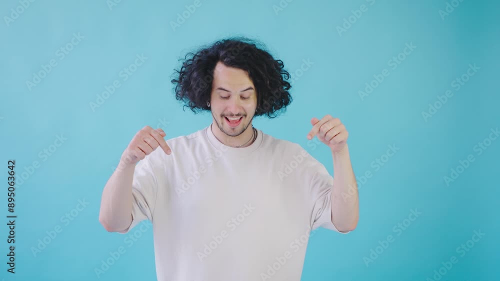 In front of a vivid blue backdrop, a cheerful young man with curly hair exudes happiness and positivity in a candid and friendly manner, embodying a blissful and joyful expression In front of a vivid blue backdrop, a cheerful young man with curly hair exudes happiness and positivity in a candid and friendly manner, embodying a blissful and joyful expression