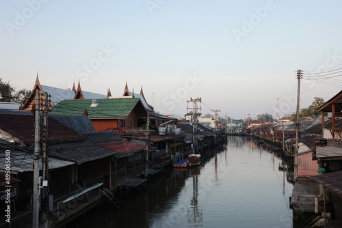 Bild auf Leinwand Traditional Thai riverside houses along a calm canal in Thailand during sunset, reflecting local culture, architecture, and peaceful waterfront lifestyle