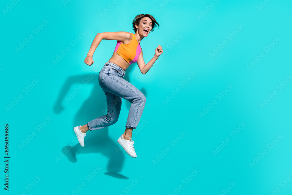 Full length photo of excited funky lady dressed colorful top jumping high hurrying empty space isolated turquoise color background Full length photo of excited funky lady dressed colorful top jumping high hurrying empty space isolated turquoise color background