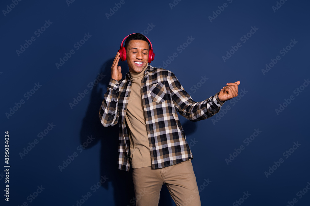 Photo of handsome good mood guy wear checkered shirt dancing enjoying music headphones emtpy space isolated blue color background Photo of handsome good mood guy wear checkered shirt dancing enjoying music headphones emtpy space isolated blue color background