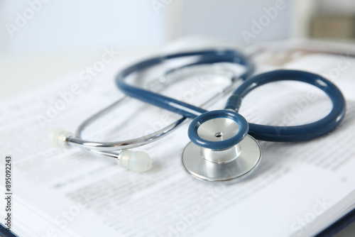 One medical stethoscope and book on table, closeup