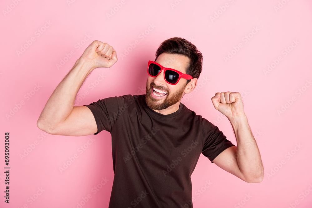 Naklejka premium Photo of overjoyed man with bristle dressed brown t-shirt in sunglass raising fists celebrate party isolated on pink color background