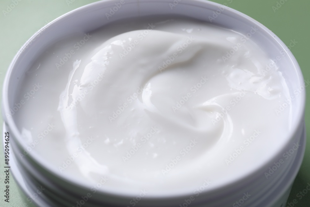 Face cream in jar on green background, closeup Face cream in jar on green background, closeup