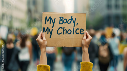 A pair of hands holding a sign that reads My Body, My Choice, blurred crowd in the background  photo