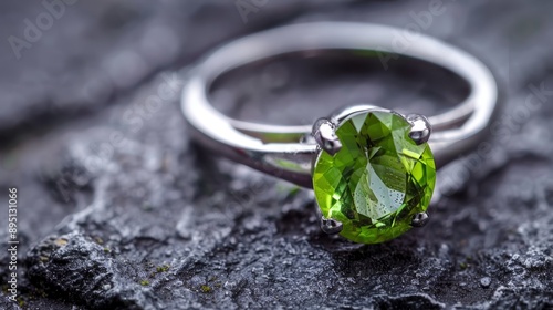  A tight shot of a ring atop a rock, featuring a green gemstone in its center, and another identical green gemstone nestled in the ring's core